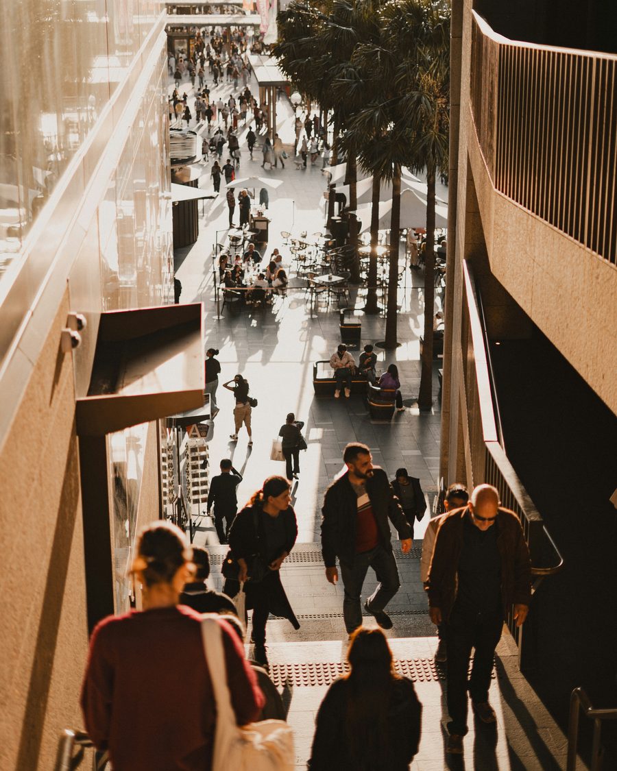 Gente caminando por una calle comercial, dos personas se cruzan de frente