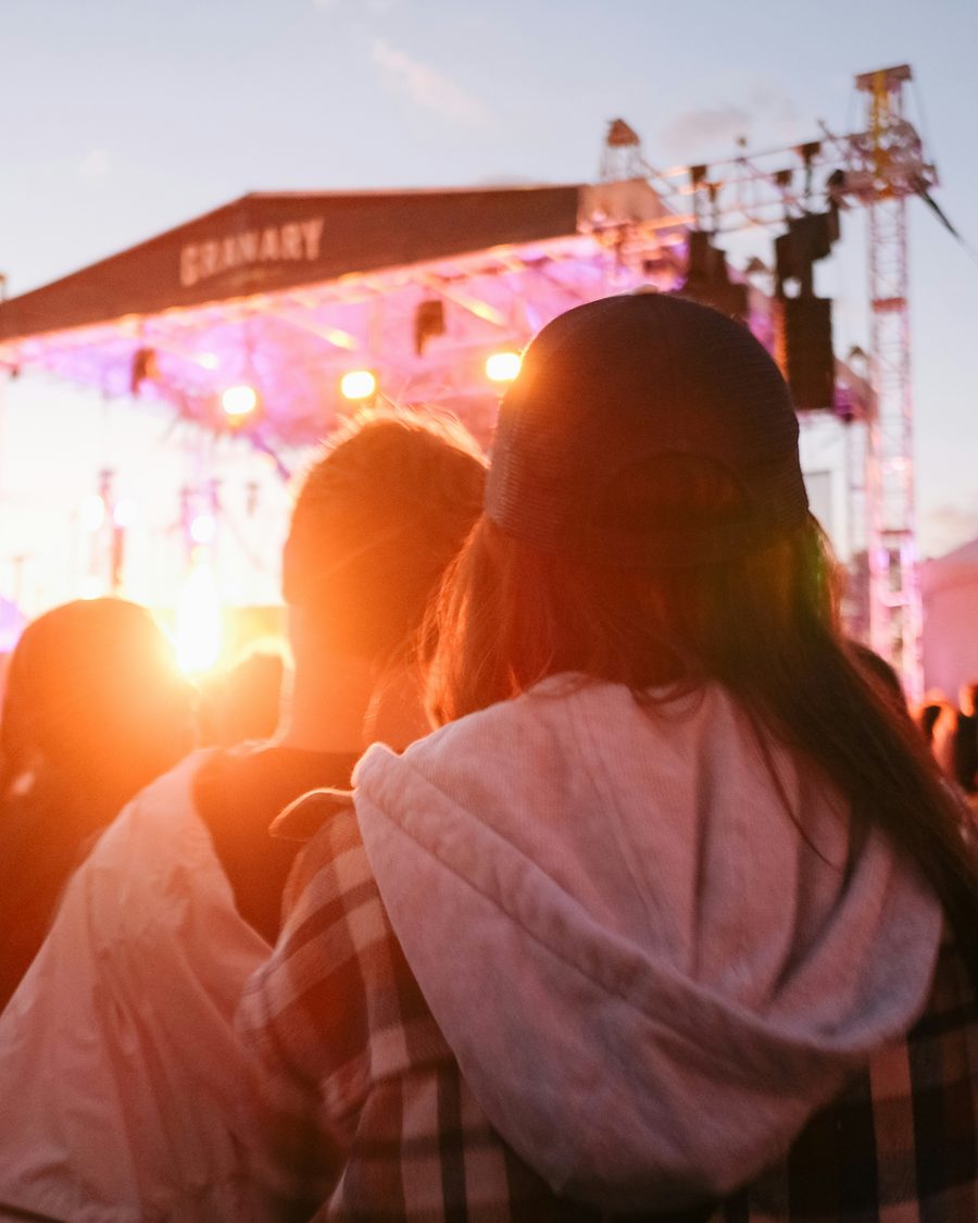 Multitud en un recital al atardecer, una persona se da vuelta entre la gente